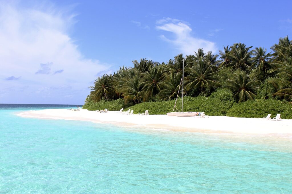 Weißer Sandstrand mit Palmen und türkisem Wasser auf einer Local Island der Malediven