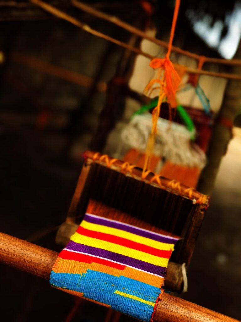Kente-Weber an traditionellem Webstuhl in Bonwire, Ghana